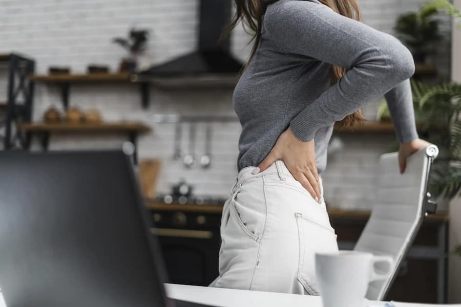 Mujer con dolor lumbar trabajando frente al ordenador tratada en FisioSpace Madrid